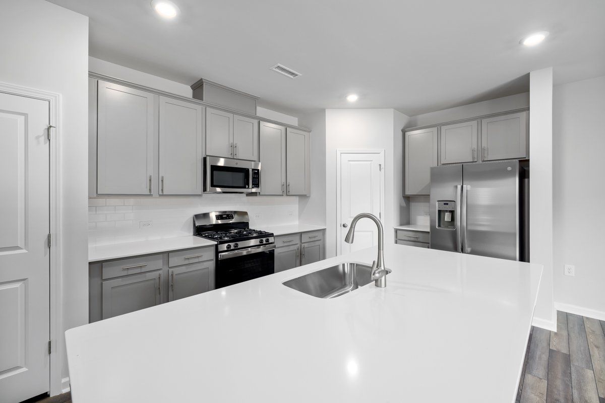 A kitchen with stainless steel appliances and white counter tops.