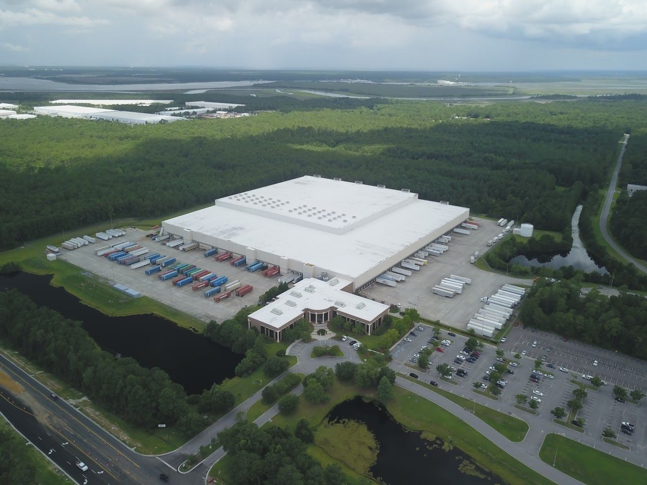 An aerial view of a large white building surrounded by trees and a parking lot.