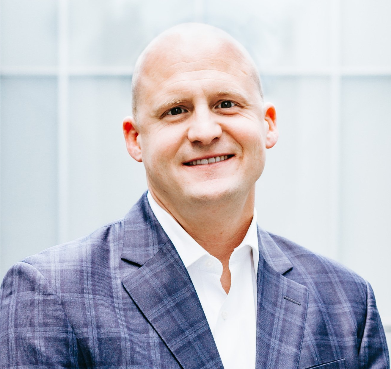 A man in a suit and white shirt is smiling for the camera.