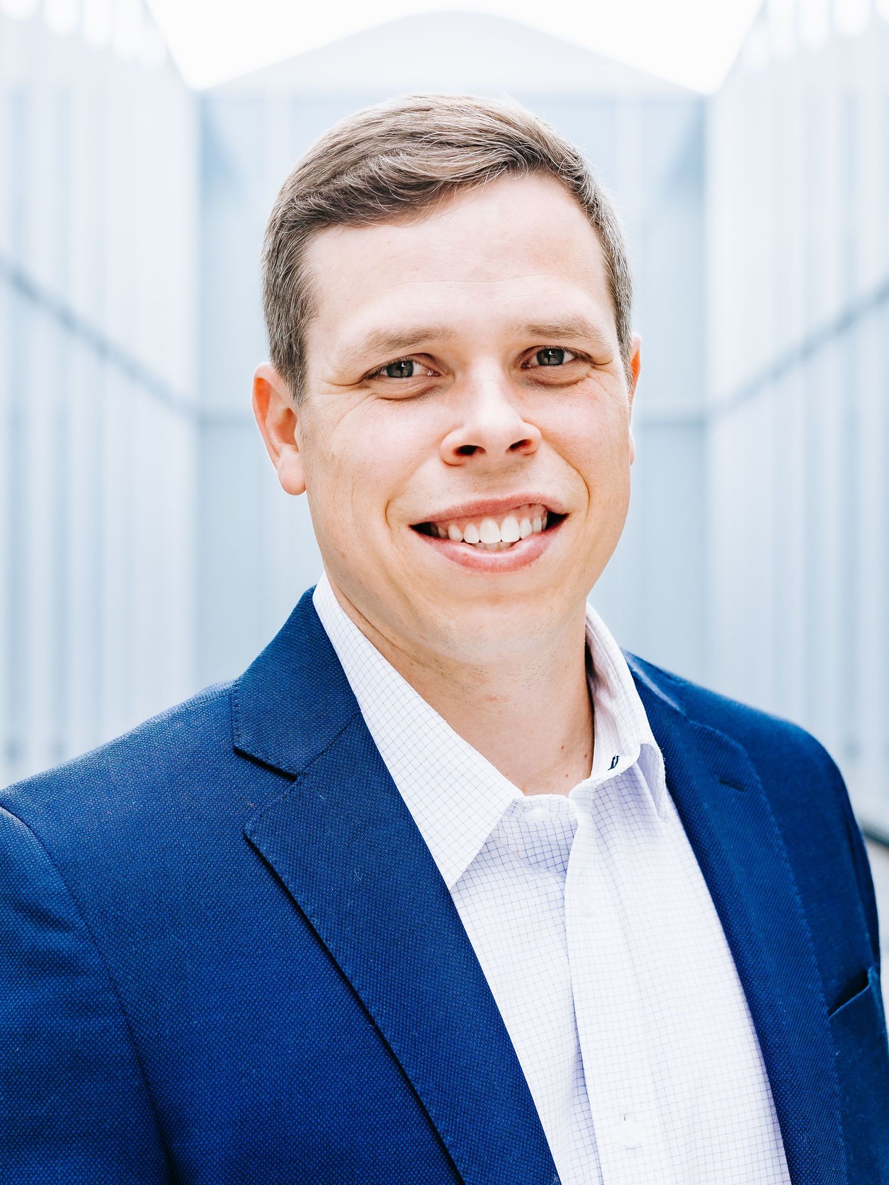 A man in a blue suit and white shirt is smiling for the camera.