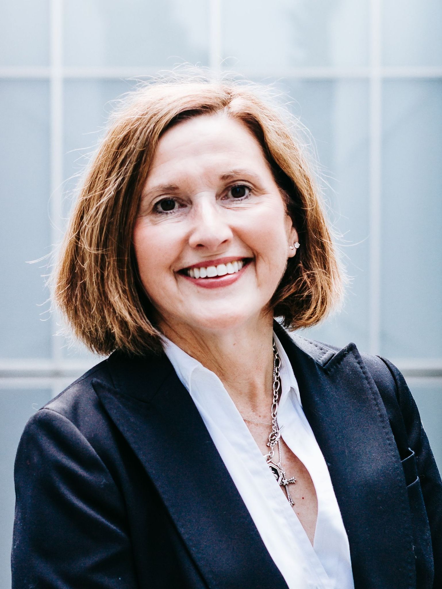 A woman in a black jacket and white shirt is smiling for the camera.