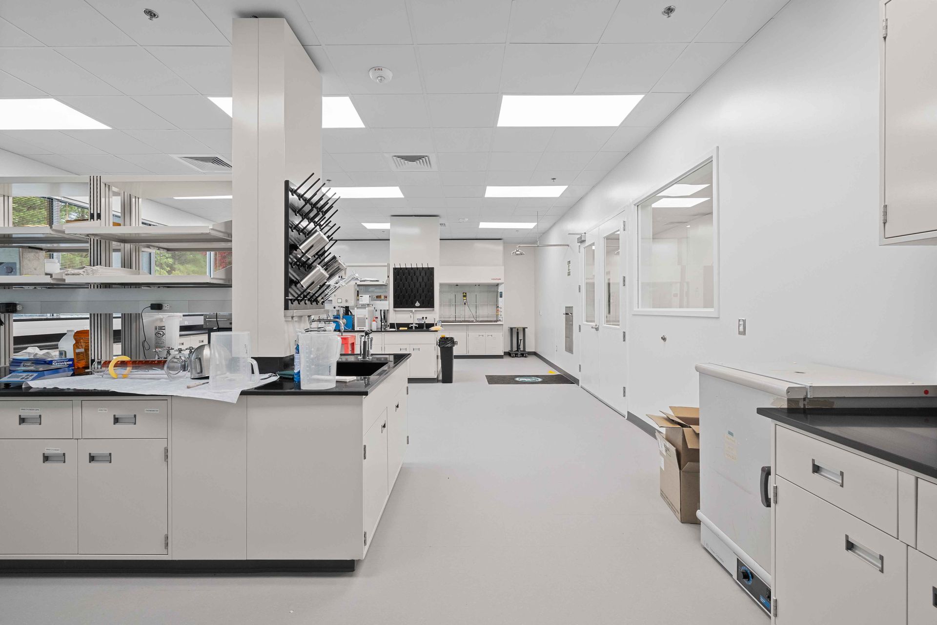 A brightly lit, modern scientific laboratory featuring white counters, storage cabinets, and stainless steel equipment.