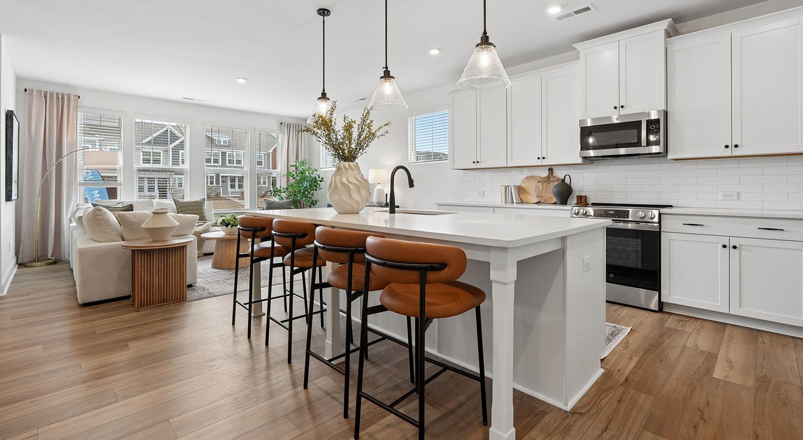 Bright modern kitchen with white cabinets, marble island, bar stools, and an adjacent dining area