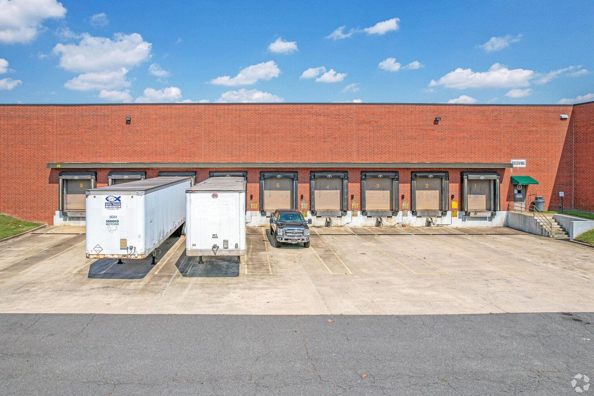 A warehouse with a lot of trucks parked in front of it.