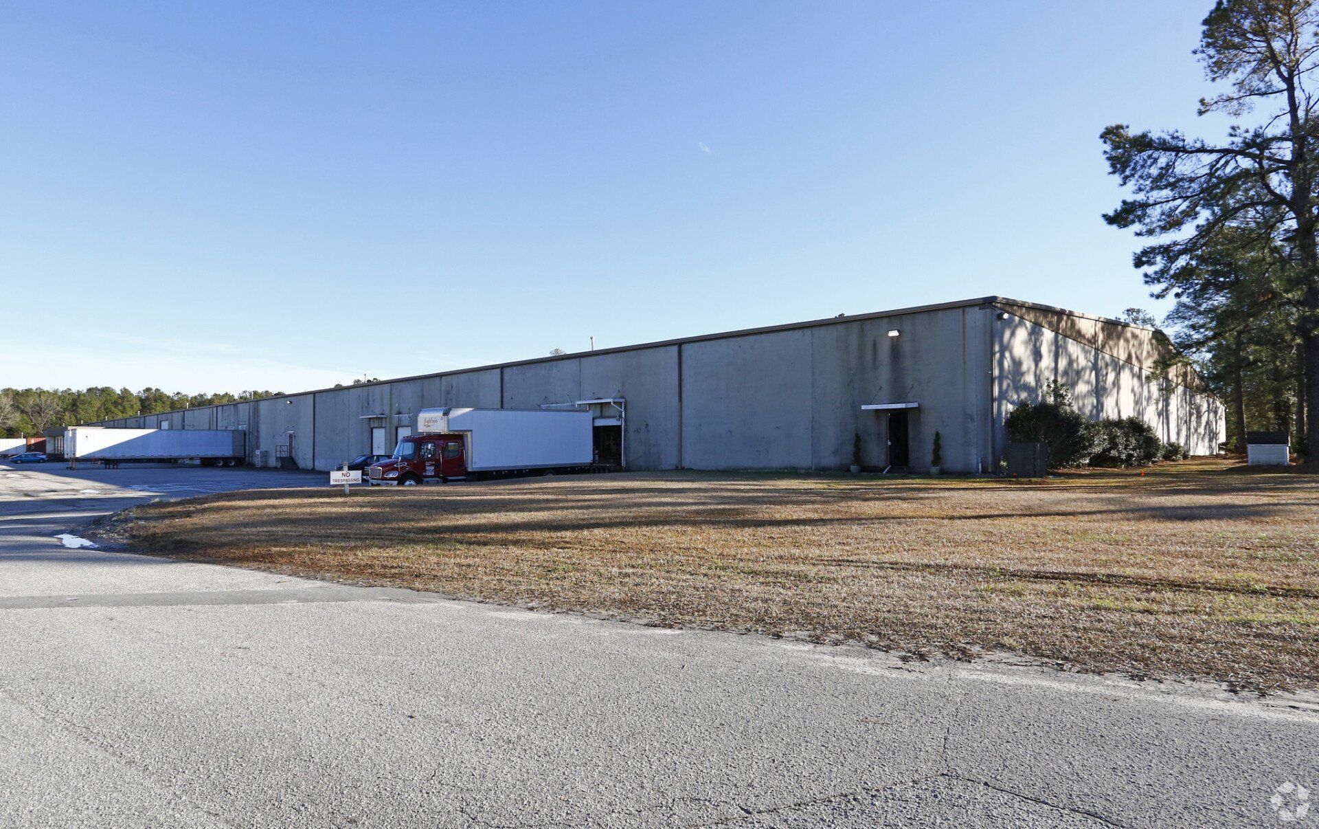 A large warehouse with a lot of trucks parked in front of it