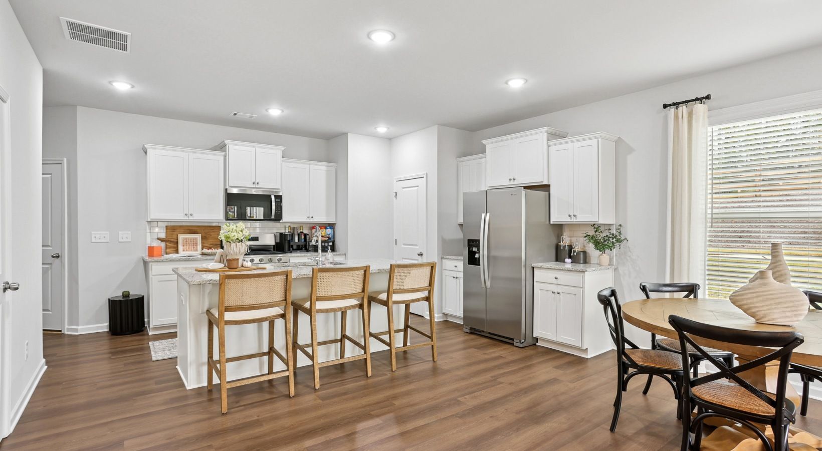 An artist 's impression of a kitchen with white cabinets and stools.