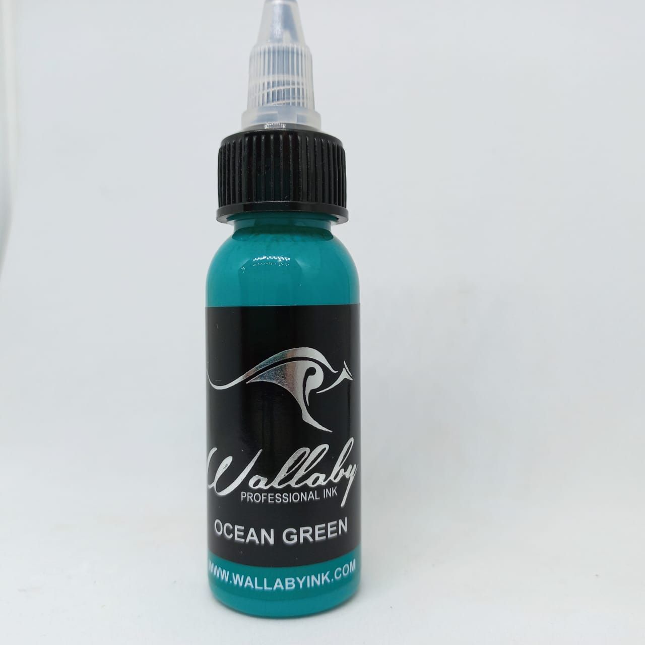 Botellita turquesa con etiqueta negra y tapón cuentagotas, con el nombre «Ocean Green»