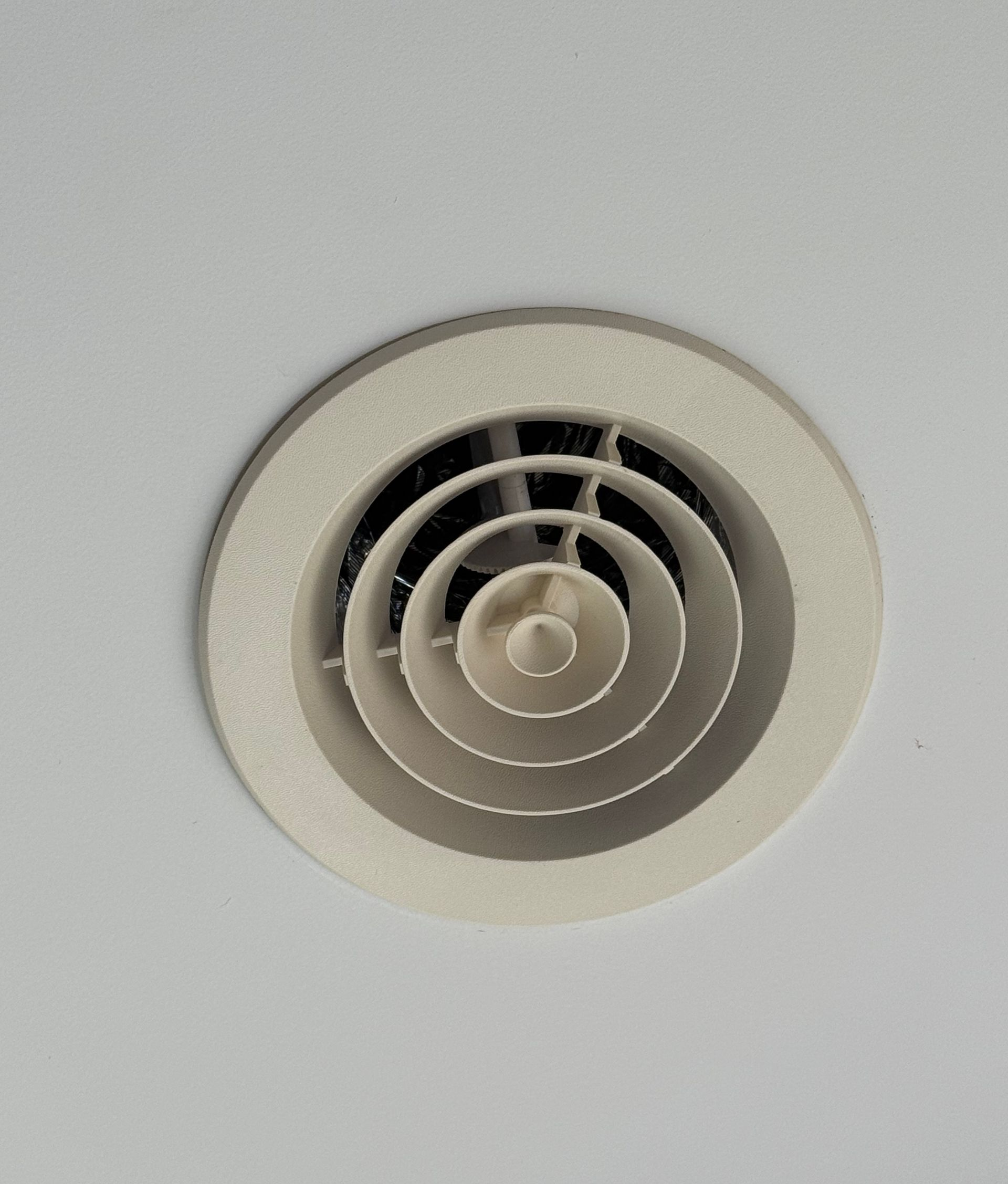 A beige, circular multi-layered ceiling air vent mounted on a white surface. — Priest Airconditioning in Ashmont, NSW