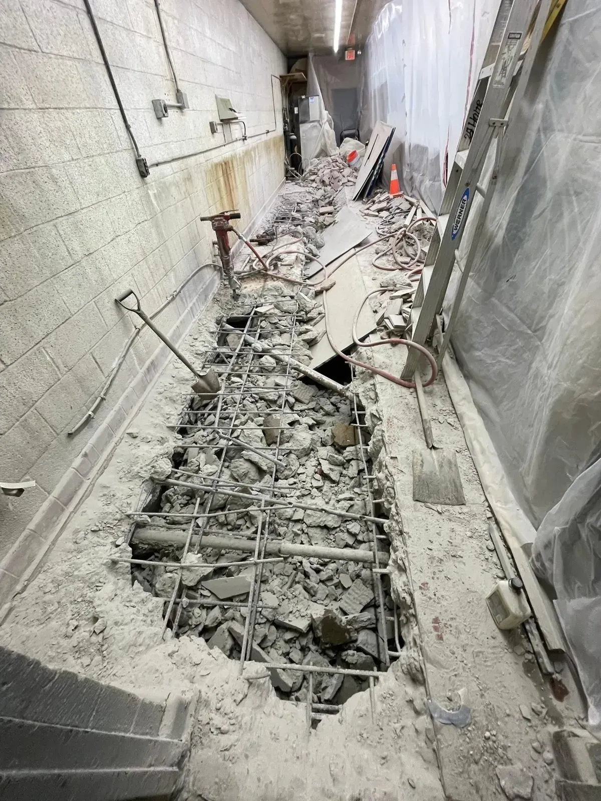 Damaged concrete corridor with collapsed floor, exposed rebar, and rubble debris