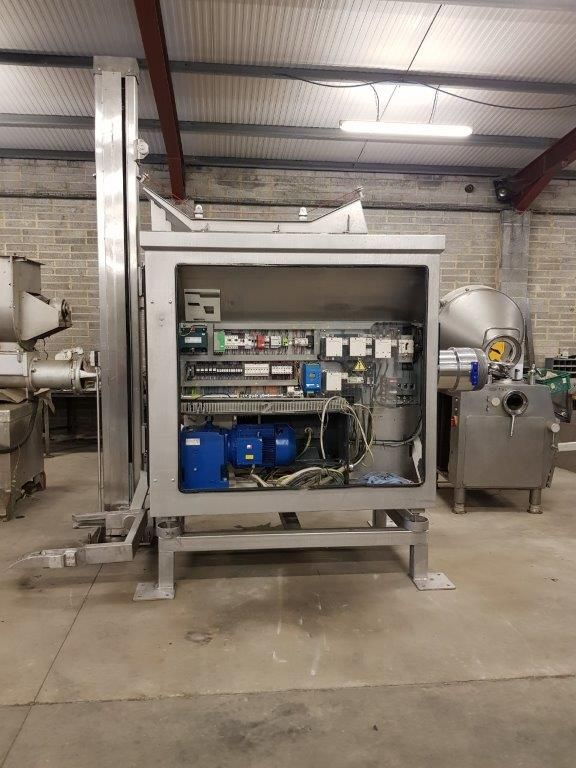 Stainless steel industrial control box with electrical components and machinery in a warehouse.