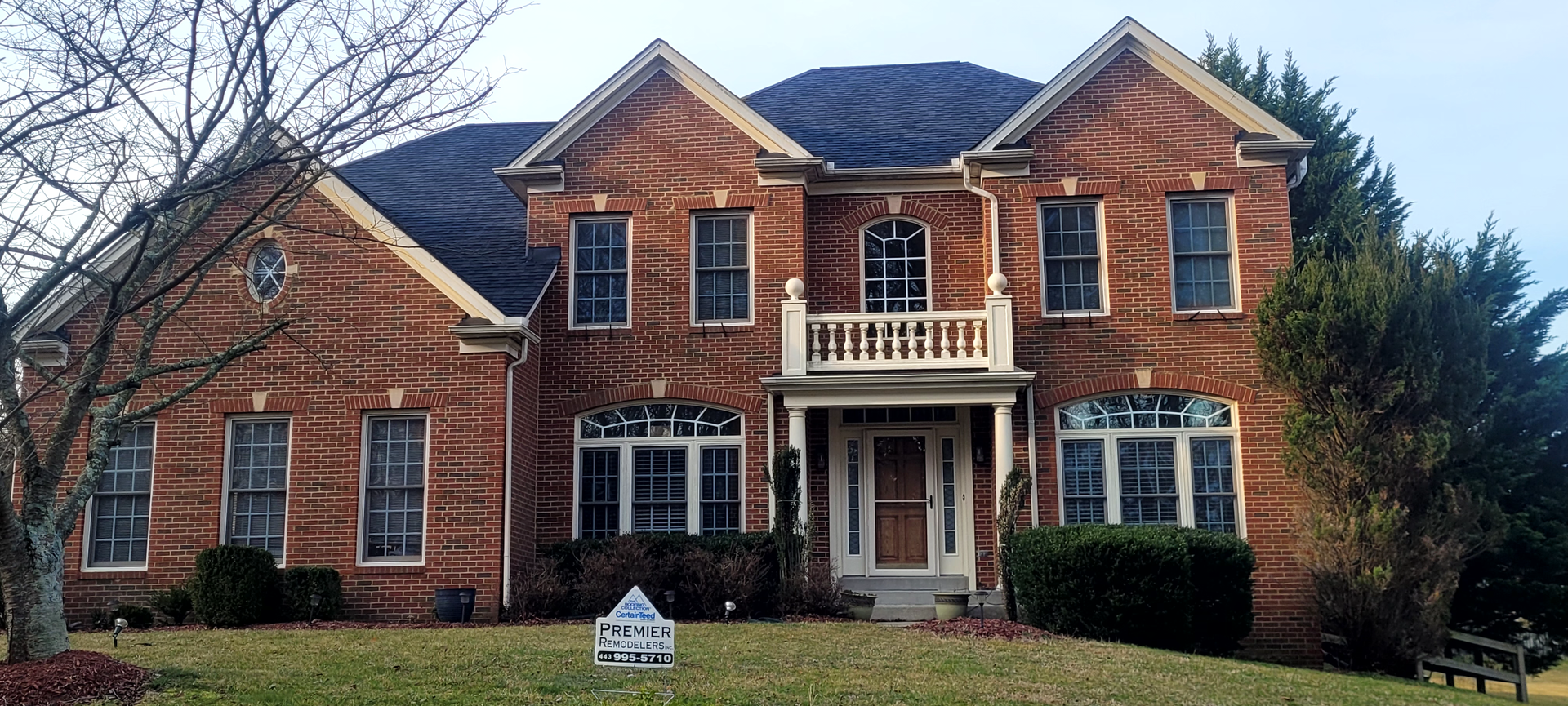 a brown house with a white garage door and a red door
