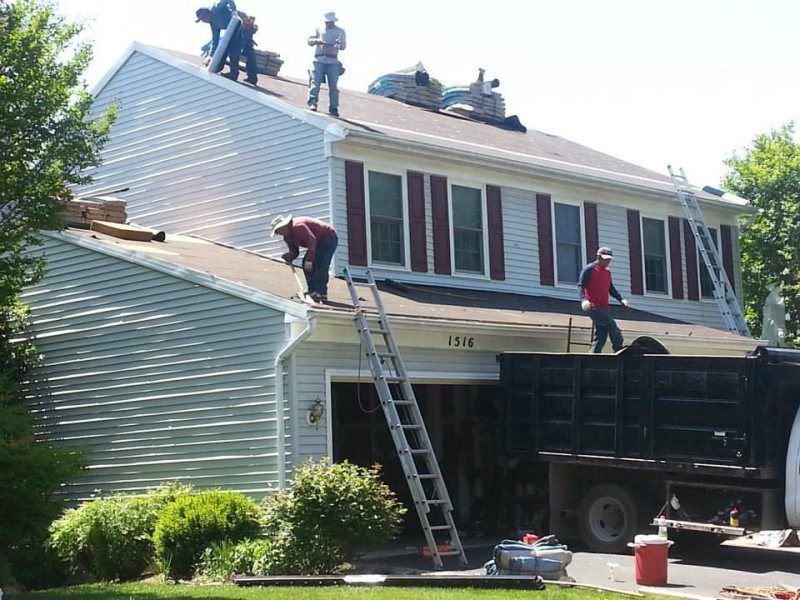 a group of men are working on the roof of a house