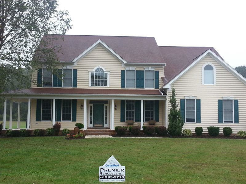 a large house with a premier roofing sign in front of it