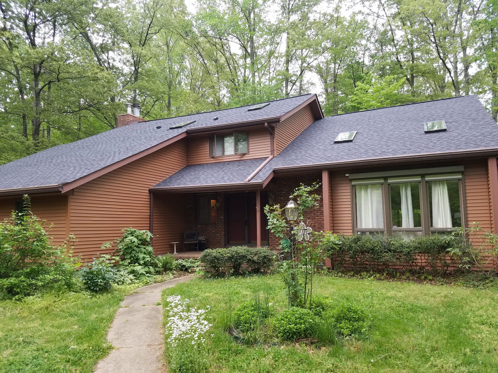 a large wooden house with a blue roof is surrounded by trees .