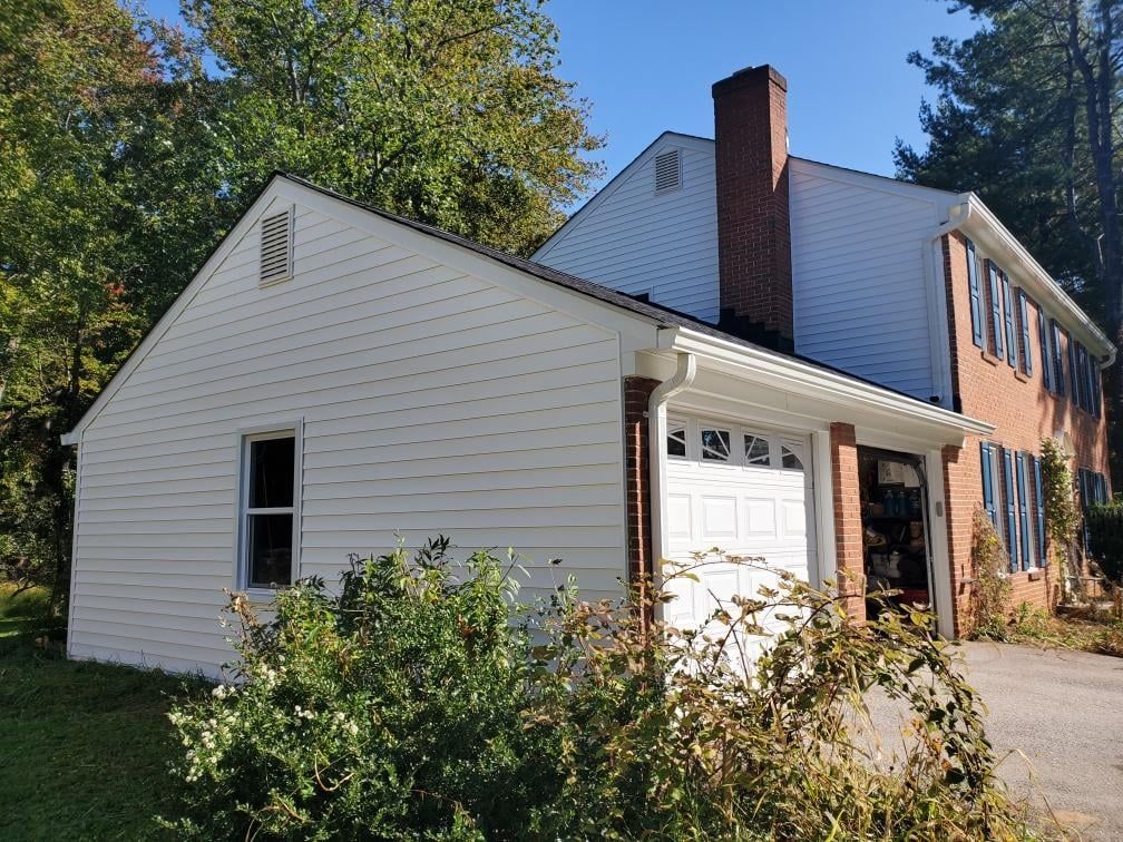 a white house with a brick chimney and a white garage door