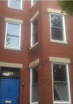 a brick building with a blue door and white windows .