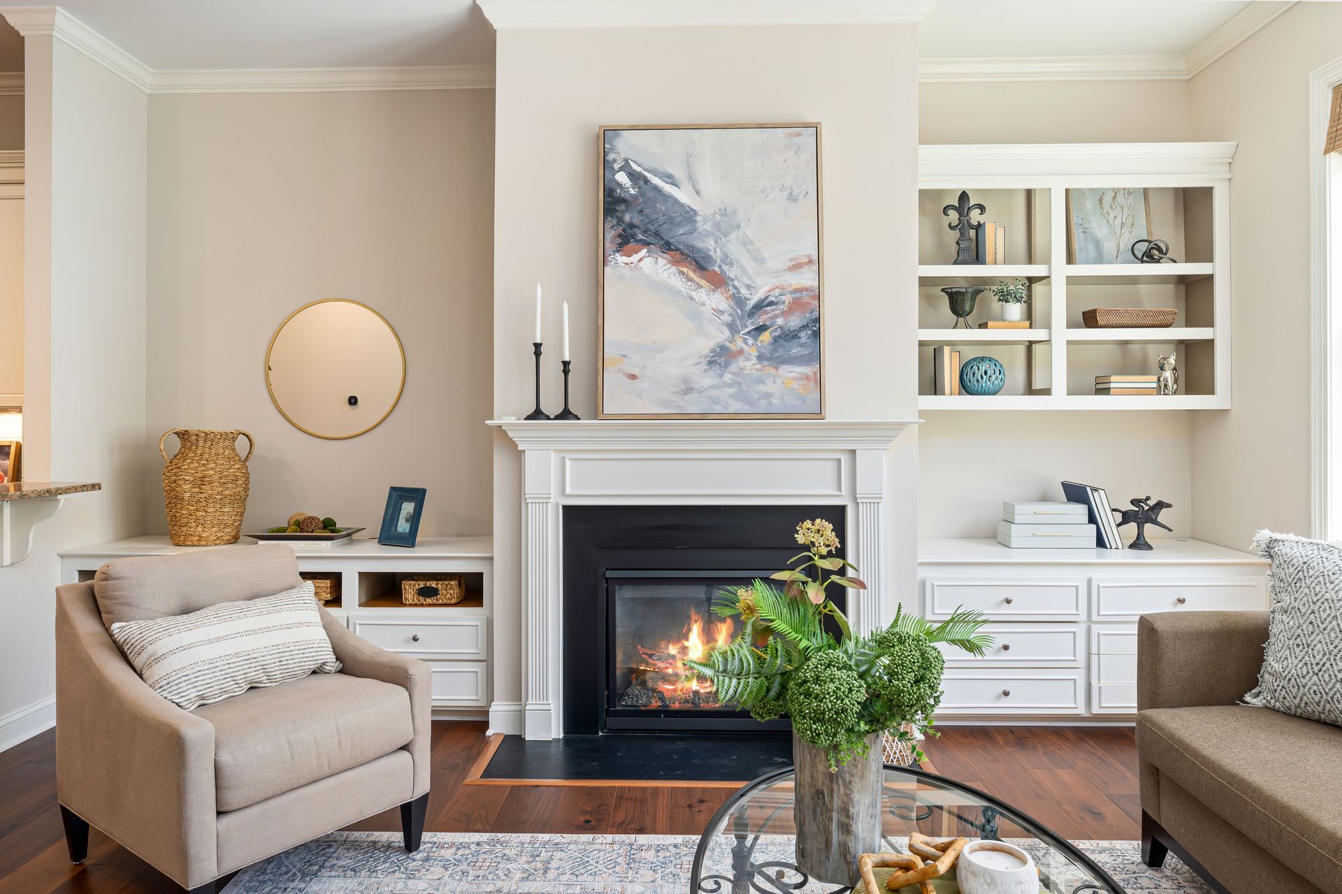 Cozy living room with beige chairs, fireplace, abstract art, and built-in shelves