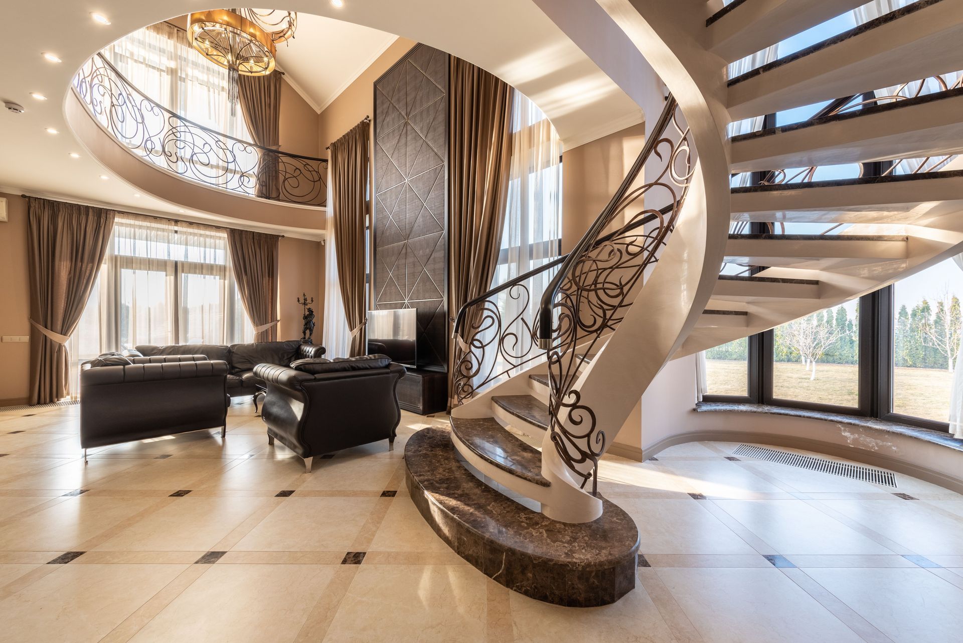 Luxury foyer with curved staircase, black seating, and floor-to-ceiling windows