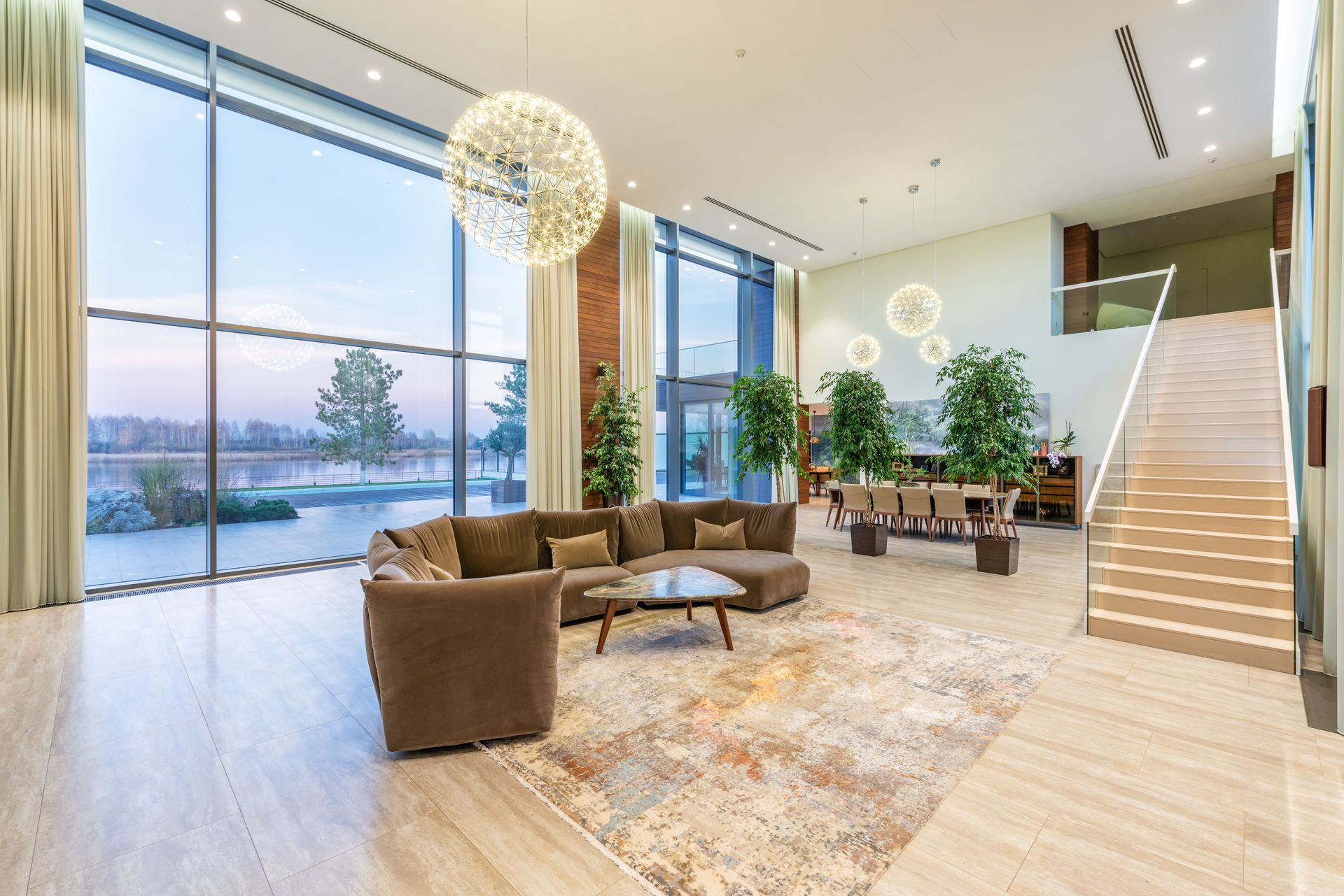 Modern hotel lobby with lounge seating, floor-to-ceiling windows, and a staircase