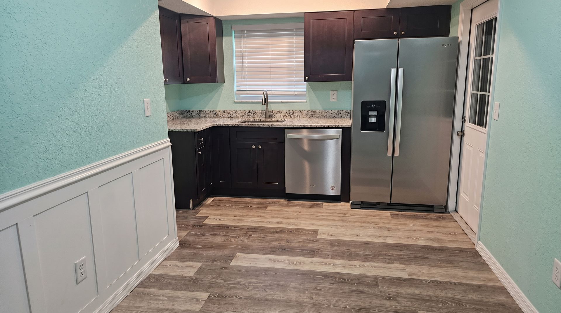 Modern kitchen with stainless steel appliances, granite countertops, white cabinets, and a gas stove
