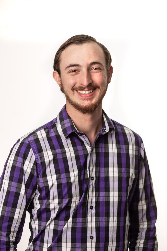 Smiling pastor in a purple plaid shirt on a white background
