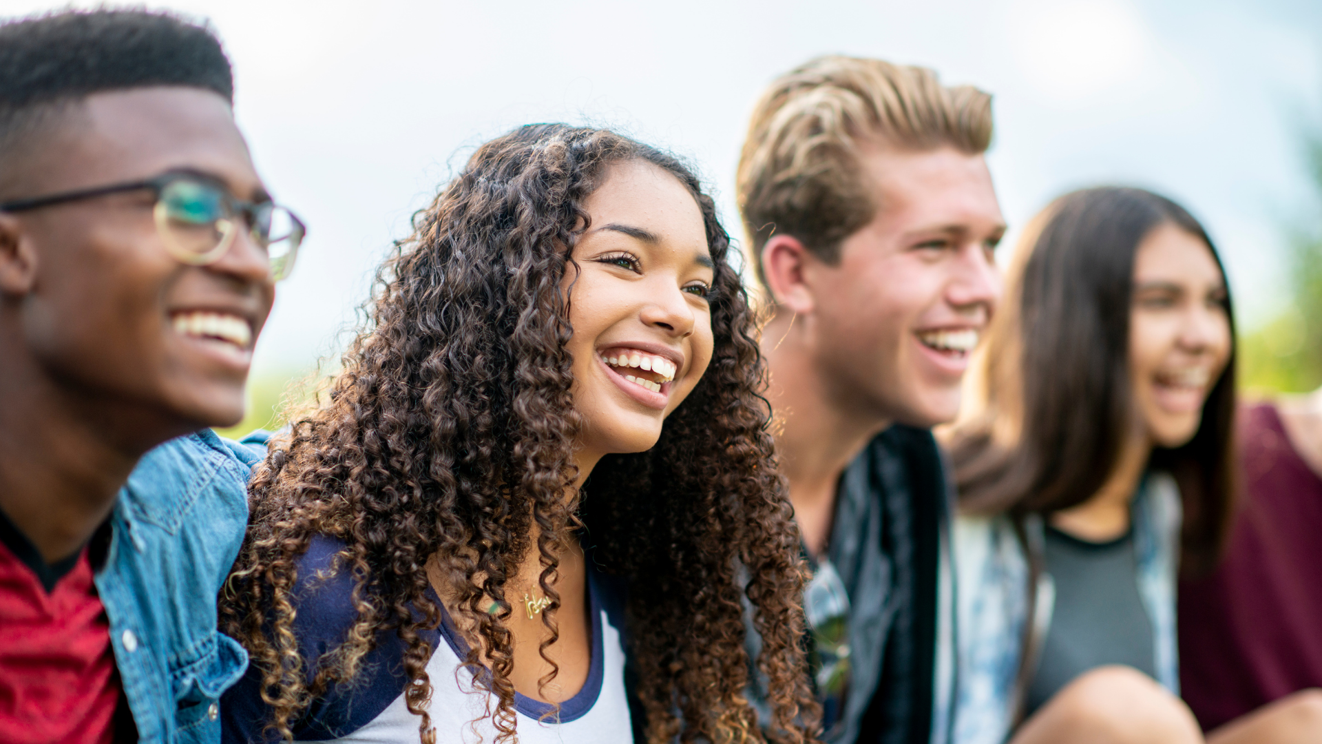 Smiling friends chatting outdoors, with a focus on two people in the foreground