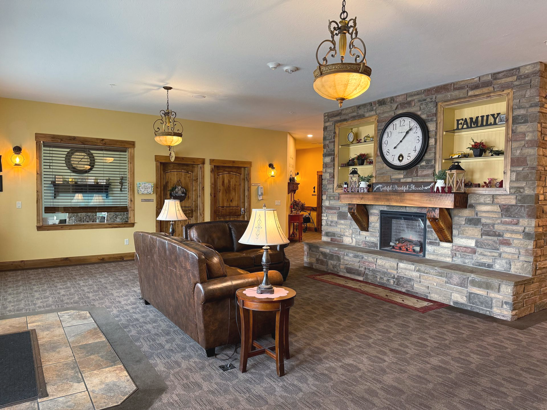Lobby with stone fireplace, leather sofa, and ornate light fixtures; warm tones and rustic decor.