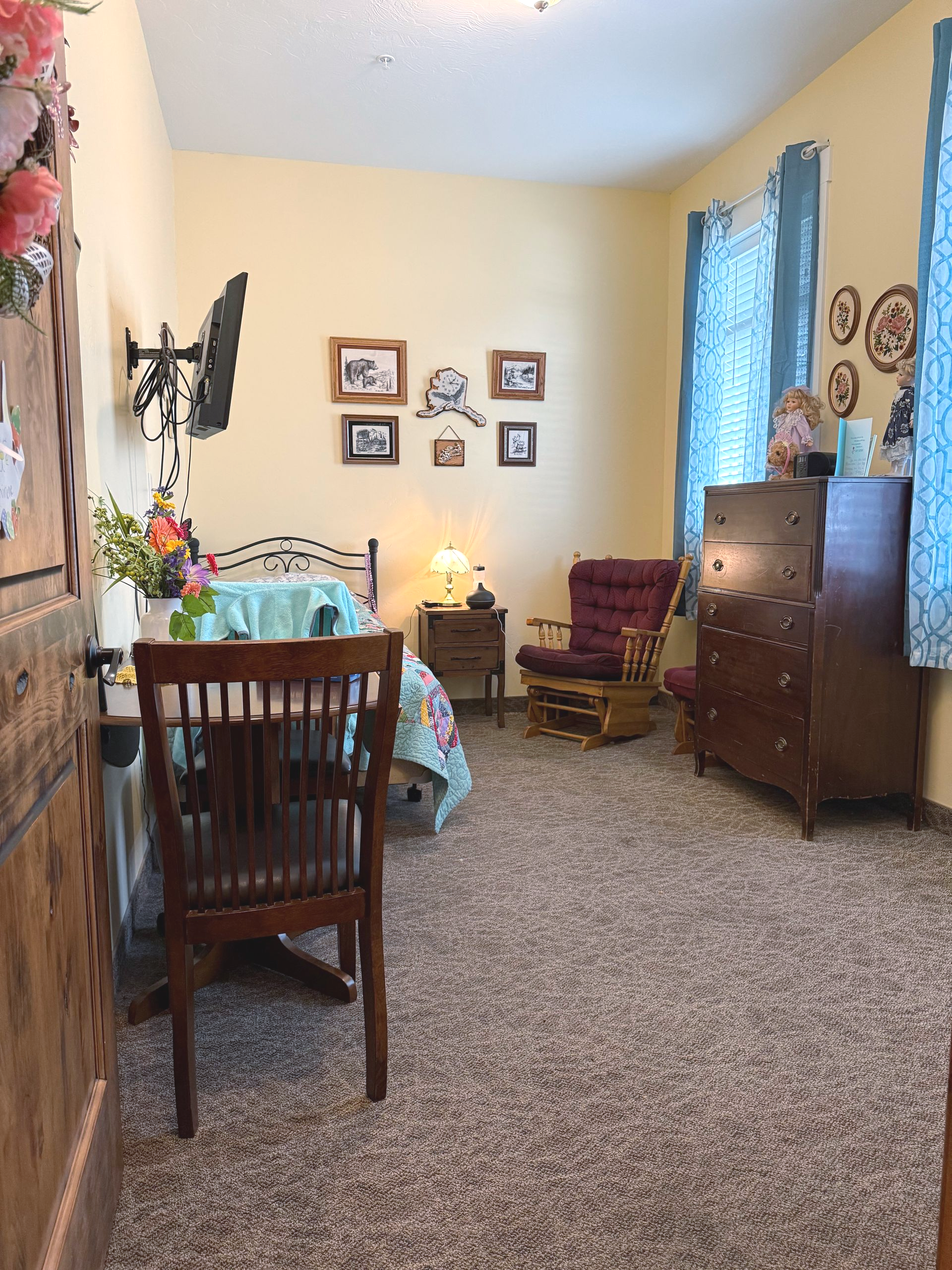 Bedroom with yellow walls, floral bedding, wood furniture, and patterned carpet.