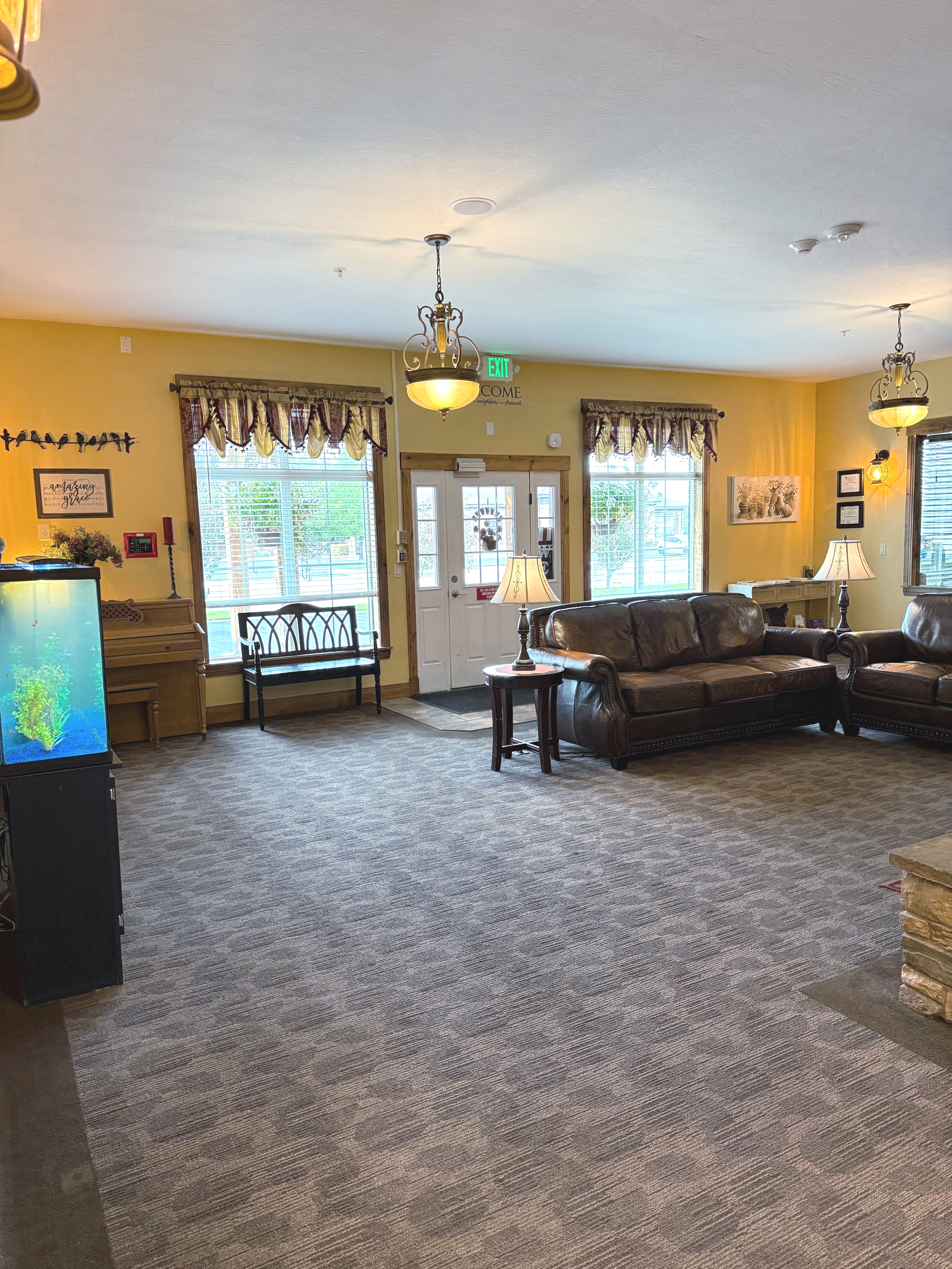 Lobby with brown leather furniture, windows with patterned curtains, and a large aquarium.