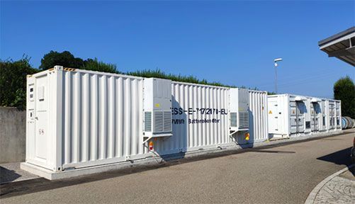 White shipping containers lined up outdoors under a clear blue sky.