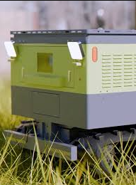 Modern beehive in green and gray tones, resting on a metal base in grass.