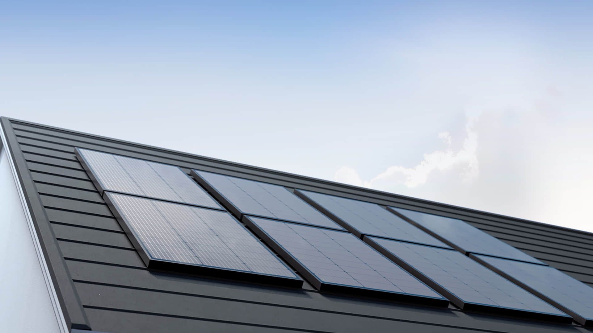Solar panels installed on a dark gray rooftop against a blue sky.