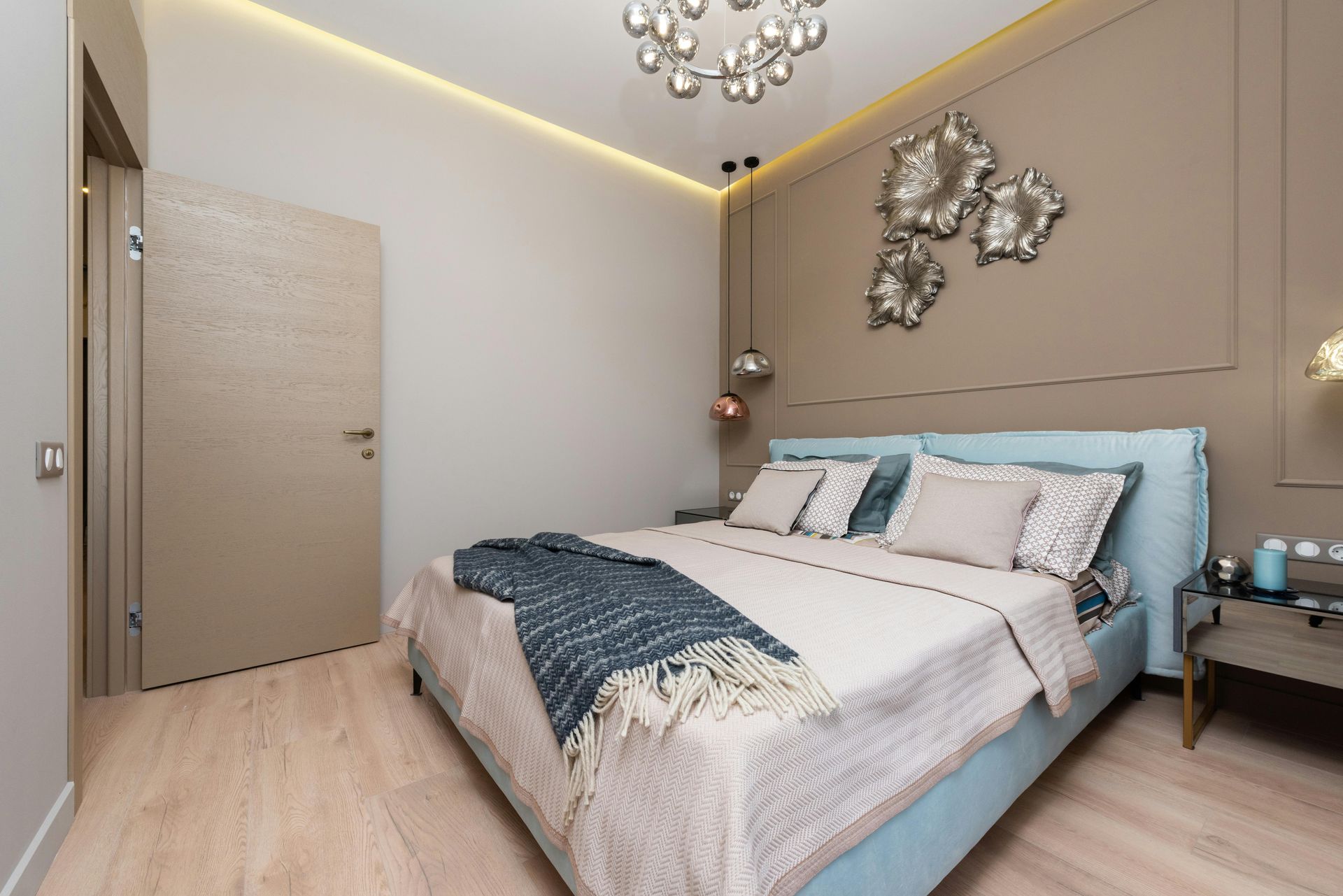 Modern bedroom with beige walls, light wood floor, a large bed, and decorative wall art.