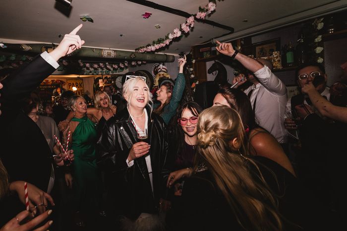 Small live music venue with seated audience watching a performer on stage under warm lighting