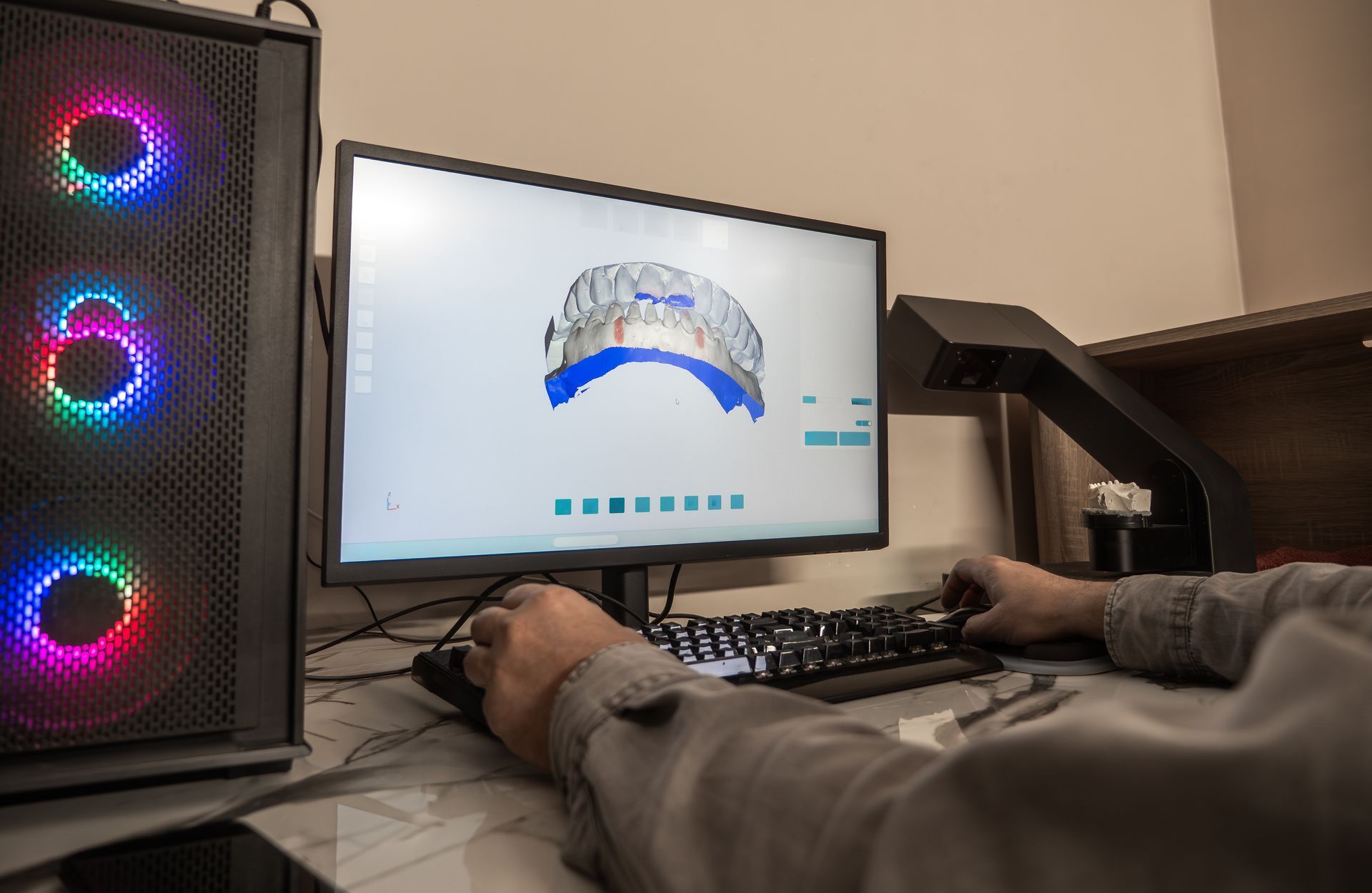 A partial view of a technician using dental CAD software showing a 3D crown model on screen. A partial view of a technician using dental CAD software showing a 3D crown model on screen.