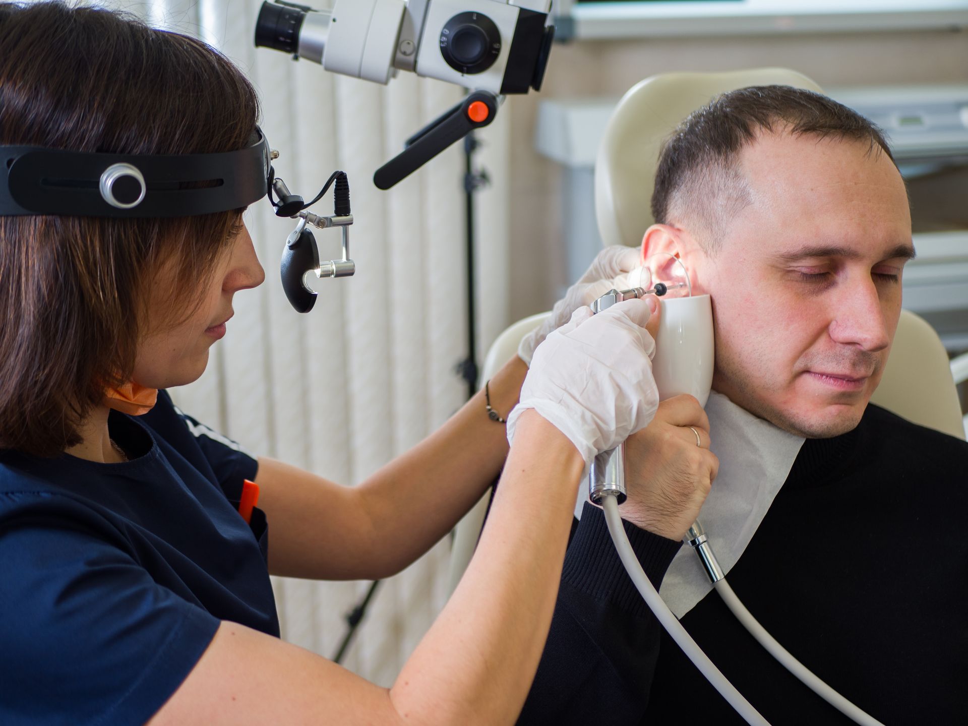 A doctor is performing a micro-ear cleaning on a male patient at a clinic. A doctor is performing a micro-ear cleaning on a male patient at a clinic.