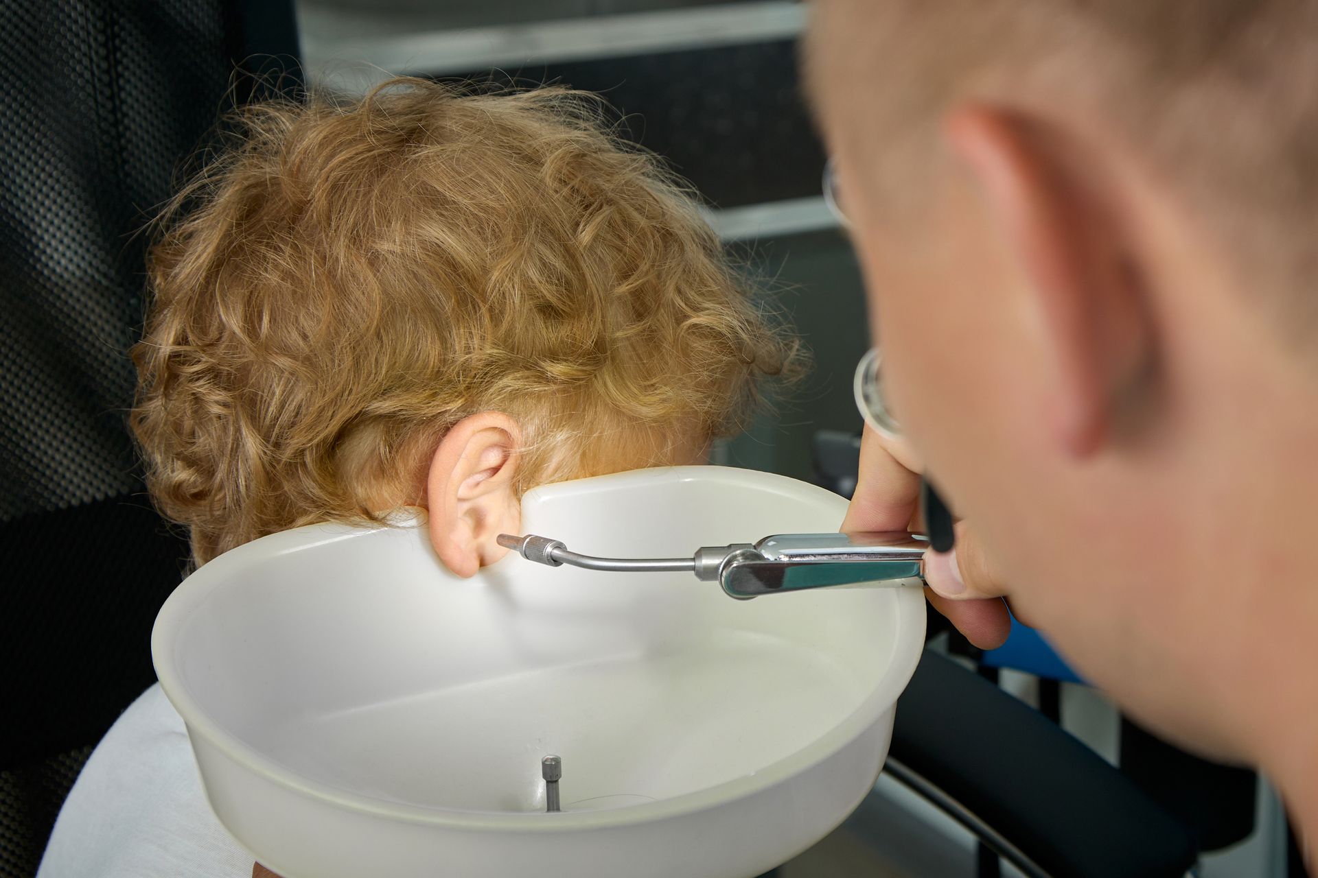 A close-up of an ear doctor cleaning a boy's right ear from an ENT room. A close-up of an ear doctor cleaning a boy's right ear from an ENT room.