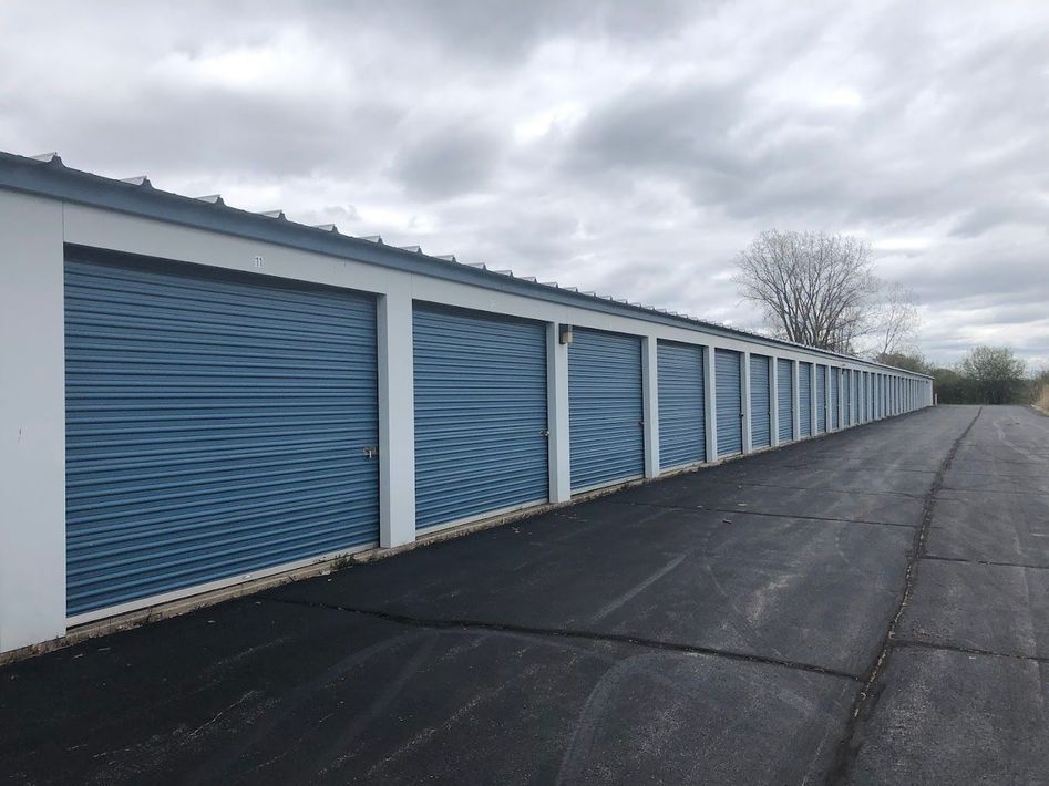 A row of storage units with blue doors on a cloudy day.