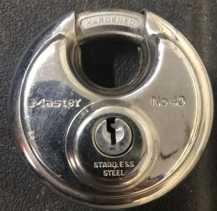 A stainless steel padlock with a key in it