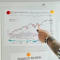 Hand pointing at a financial chart on a wall in a finance review meeting