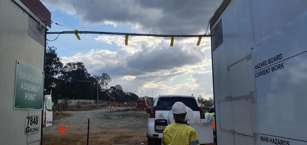 A Man in a Hard Hat is Standing in Front of a Truck in a Construction Site — D.J. Whatley & Son Pty Ltd in Logan, QLD