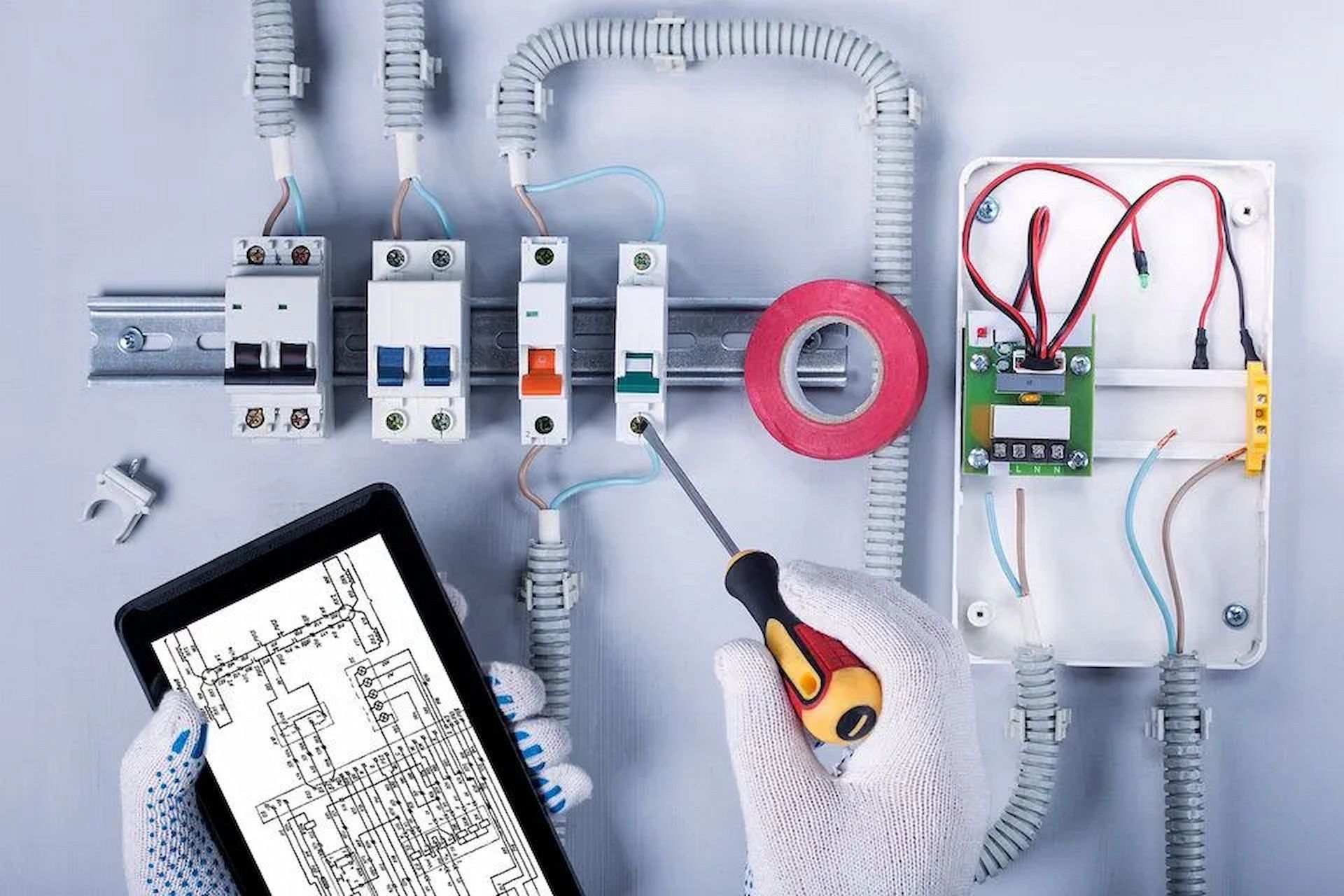 A person is holding a screwdriver next to a tablet. — D.J. Whatley & Son Pty Ltd in Ormeau Hills, QLD