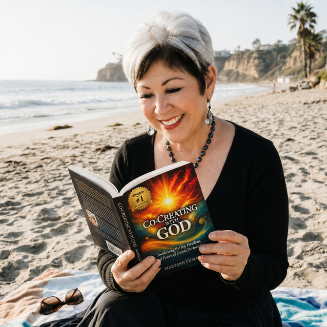 Woman reading a “Communicating God” book on a sunny beach towel by the ocean