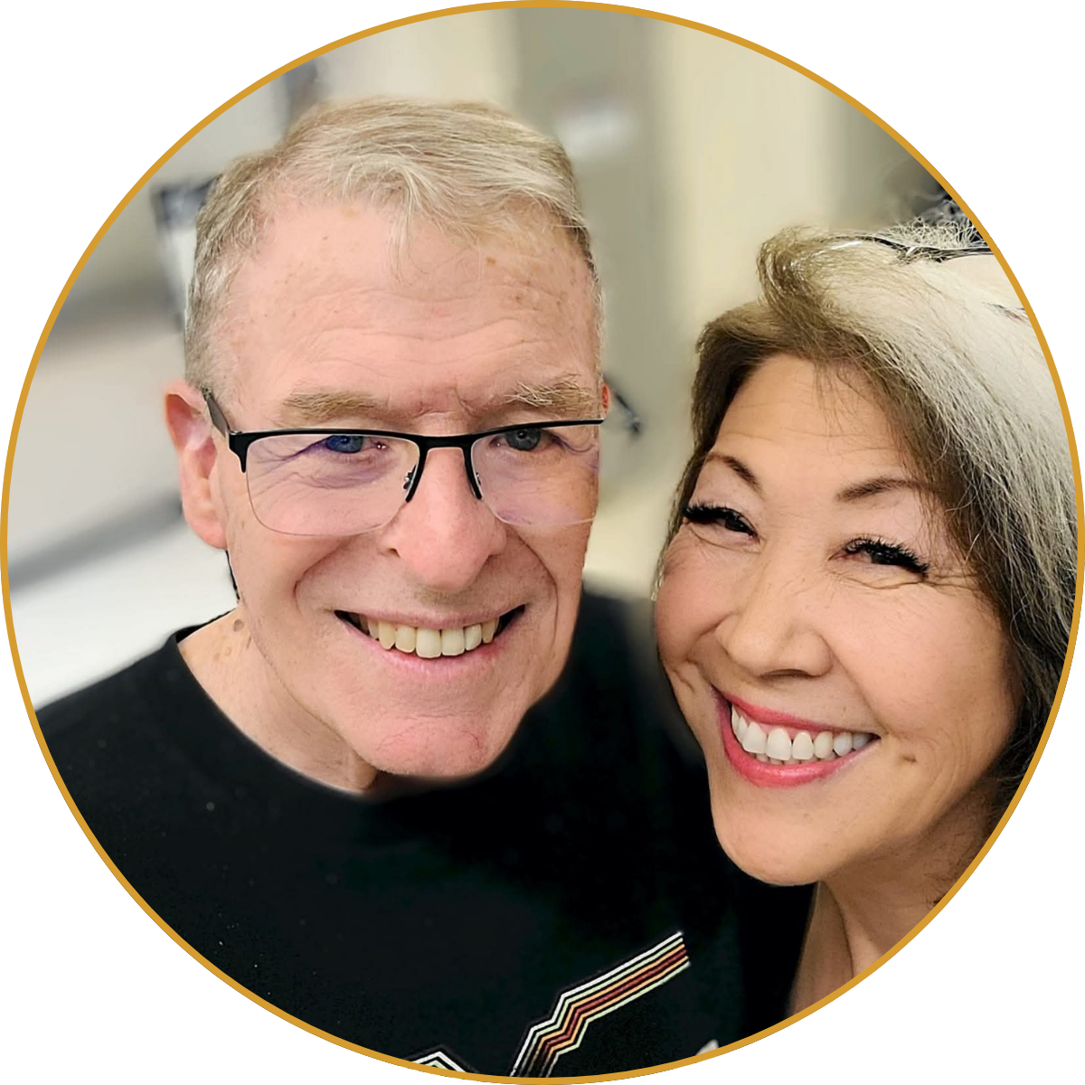 Two smiling people posing closely for a selfie against a light background