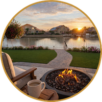 Backyard patio with fire pit and chair overlooking a sunset-lit pond and suburban homes