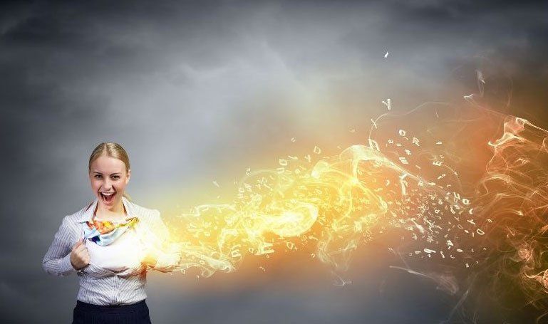 Woman holding glowing sparks from her hands against a gray background
