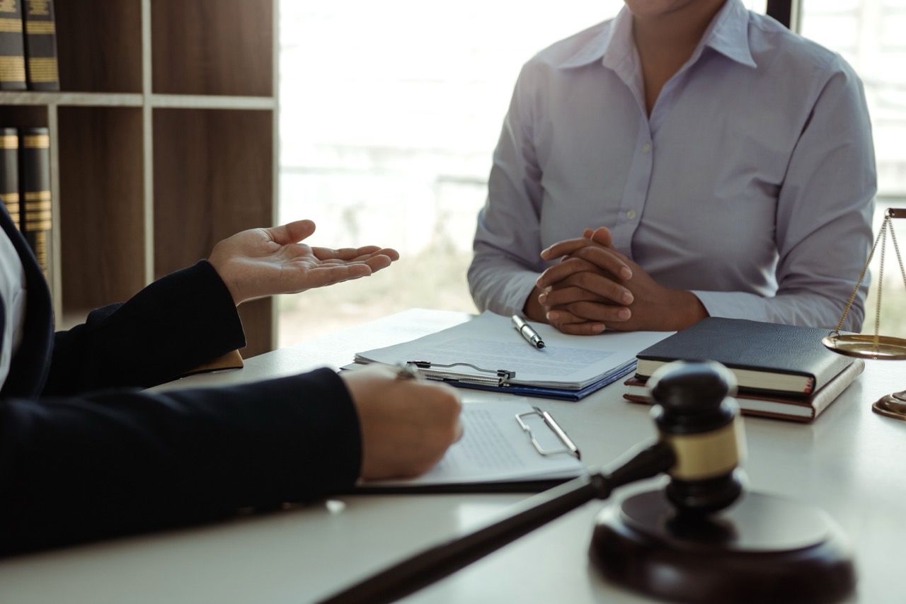 Business meeting with two people at a table, papers and a gavel in the foreground.