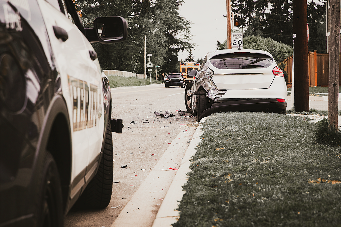 Dark sedan rear-ended by tan SUV, with severe crumpled damage on a wet road.
