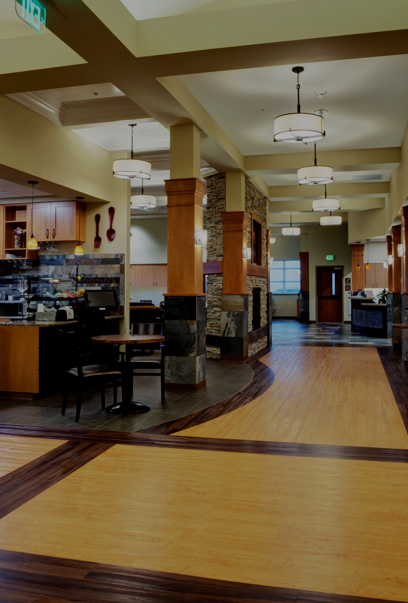 Empty hotel lobby with warm lighting, wooden floors, and a curved reception area.