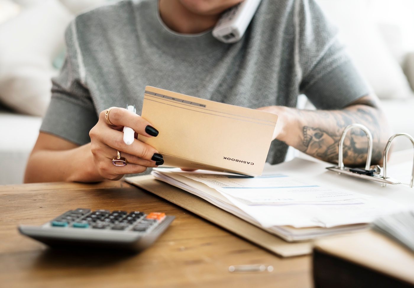 Person reviewing documents and holding an envelope at a desk with a calculator.